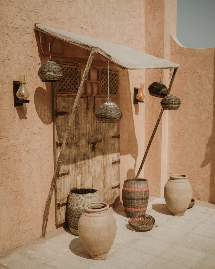 A wooden doorway with hanging baskets and clay vessels